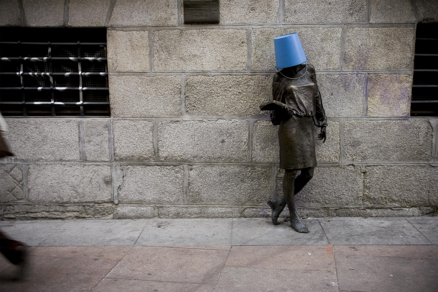 Bronzestatue einer Frau mit blauem Kübel auf dem Kopf