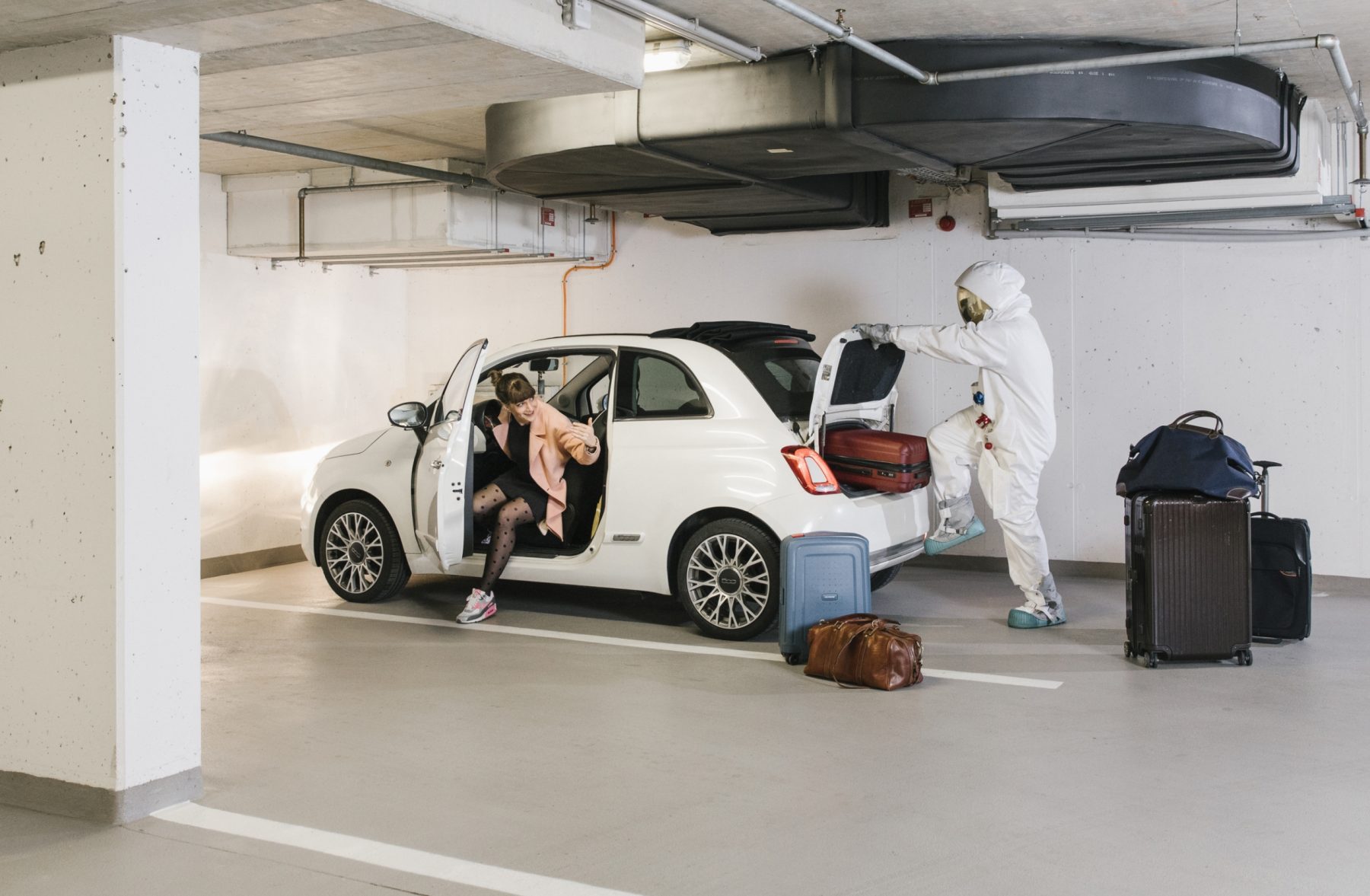Kampagnen Foto für epunkt von einem Astronaut, der Koffer in den Kofferraum eines weißen Autos packt